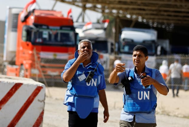  UN workers gesture as trucks carrying aid arrive at the Palestinian side of the border with Egypt, as the conflict between Israel and Palestinian terrorist group Hamas continues, in Rafah in the southern Gaza Strip, October 21, 2023.  (photo credit:  REUTERS/Ibraheem Abu Mustafa)