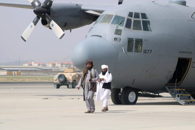  TALIBAN MEMBERS walk in front of a military airplane a day after the US withdrawal, in Kabul, August 31, 2021.  (photo credit: REUTERS)