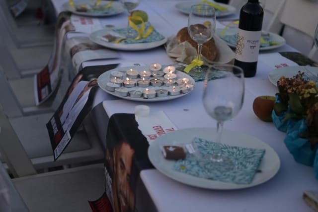 A symbolic Shabbat dinner table is set as families of hostages vow to not return home until their loved ones are freed. (photo credit: AVSHALOM SASSONI/ MAARIV)