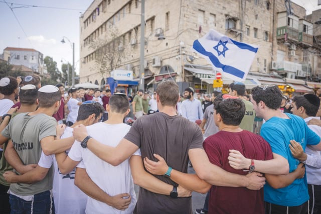  YOUTHS DANCE and wave the flag near Mahaneh Yehuda market in Jerusalem, after the start of the Gaza War. (photo credit: Chaim Goldberg/Flash90)
