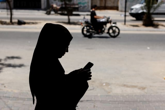  A Palestinian woman uses a Phone app that allows Gaza women to report domestic abuse anonymously, outside Gaza Women's Center in Gaza City May 31, 2022 (photo credit: REUTERS/MOHAMMED SALEM)