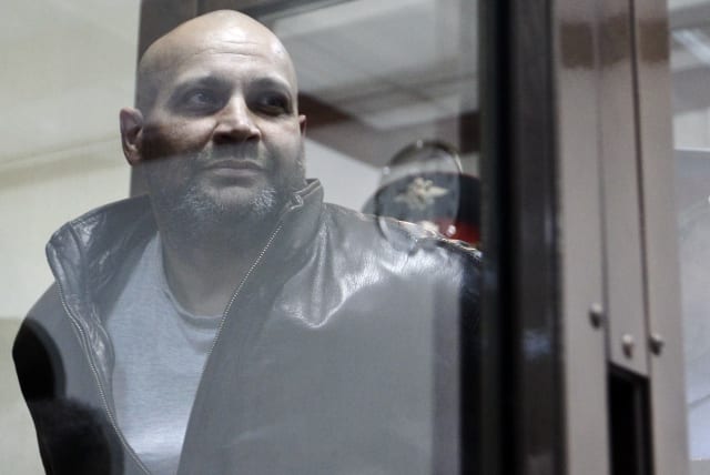  Khadzhikurbanov is escorted into a glass-walled cage before a court hearing in Moscow (photo credit: REUTERS)