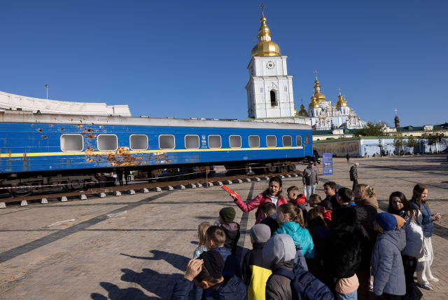  Children look at a war-damaged train carriage on display in St Michael's Square in Kyiv, amid Russia's attack on Ukraine, November 3, 2023. (photo credit: THOMAS PETER/REUTERS)