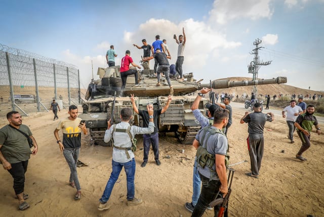 Palestinians take control of an Israeli tank after crossing the border fence with Israel from Khan Yunis in the southern Gaza Strip, October 7, 2023.  (photo credit: ABED RAHIM KHATIB/FLASH90)