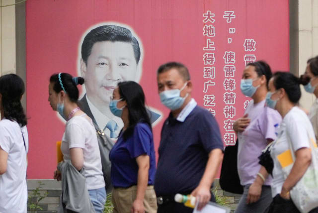  People wearing masks pass by portraits of Chinese President Xi Jinping, following the coronavirus disease (COVID-19) outbreak, in Shanghai, China, August 31, 2022 (photo credit: REUTERS/ALY SONG)