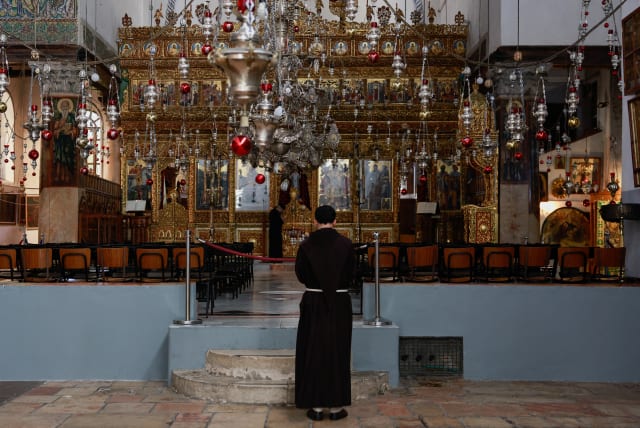  A monk stands inside the Church of the Nativity on the day of the launch of the beginning of the Christmas season, as the conflict between Israel and Hamas continues, in Bethlehem in the West Bank, December 2, 2023. (photo credit: REUTERS/AMMAR AWAD)
