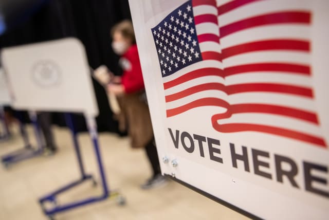  An American flag sign is seen on a voting booth at Madison Square Garden, which is used as a polling station on the first day of early voting in Manhattan, New York, U.S. October 24, 2020. (photo credit: REUTERS/JEENAH MOON)