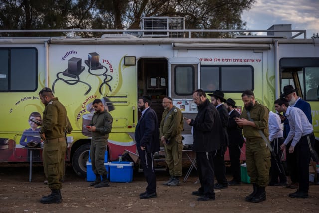  Israeli soldiers and Ultra Orthodox Jews pray at a staging area near the Israeli-Gaza border, southern Israel, November 28, 2023.  (photo credit: YONATAN SINDEL/FLASH90)