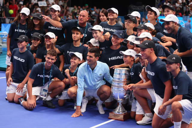  NOVAK DJOKOVIC poses with the trophy and Israeli youth tennis volunteers after winning the 2022 Tel Aviv Watergen Open, which feels like much longer than a year ago. (photo credit: NIR ELIAS/REUTERS)