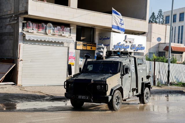  An Israeli military vehicle with an Israeli flag on top, manoeuvers on a road during a raid, amid the ongoing conflict between Israel and the Palestinian terror group Hamas, in Jenin, (photo credit: RANEEN SAWAFTA/REUTERS)
