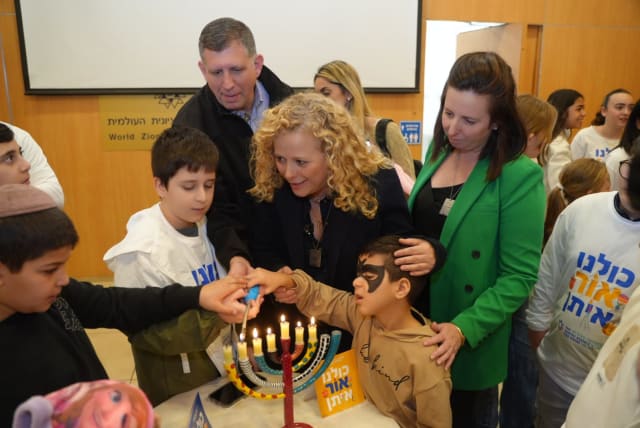  Edna Weinstock-Gabbay, CEO of Keren Hayesod, Ayelet Nahmias Verbin, Chairman of the Fund for Victims of Terror, and Sam Grundwerg Global Chairman, Keren Hayesod, light Hanukkah candles together with children at camp (photo credit: LIOR DASKAL)