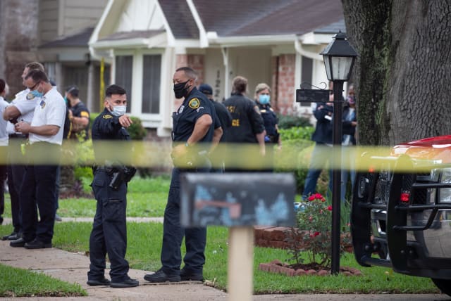 Police officials stand outside 12200 Chessington Drive in southwest Houston, Texas, U.S., April 30, 2021. Dozens of persons were found inside a residence in Southwest Houston, which was initially reported as a kidnapping but prompted police to look into human smuggling, police and local news organiz (photo credit: ADREES LATIF/REUTERS)