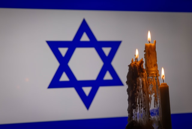 An illustration of lit candles and in the background the Israeli flag on December 17, 2023 (photo credit: Chaim Goldberg/Flash90)