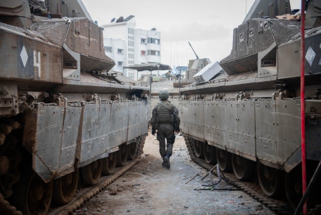  IDF soldier seen walking between two armored vehicles in Gaza, December 20, 2023.  (photo credit: IDF SPOKESPERSON'S UNIT)
