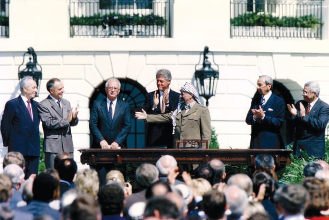  PLO chairman Yasser Arafat (third right) gestures toward prime minister Yitzhak Rabin (third left) as US president Bill Clinton (center) stands between them, after the signing of the Oslo Accords on September 13, 1993. (photo credit: GARY HERSHORN/REUTERS)