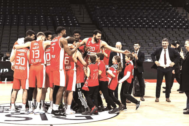   HAPOEL TEL AVIV players celebrate on the court with a number of young fans from the group of 160 war-affected supporters who were hosted by the Reds in Belgrade for Wednesday night’s 100-81 EuroCup victory over Venezia. (photo credit: Hapoel Tel Aviv/Courtesy)