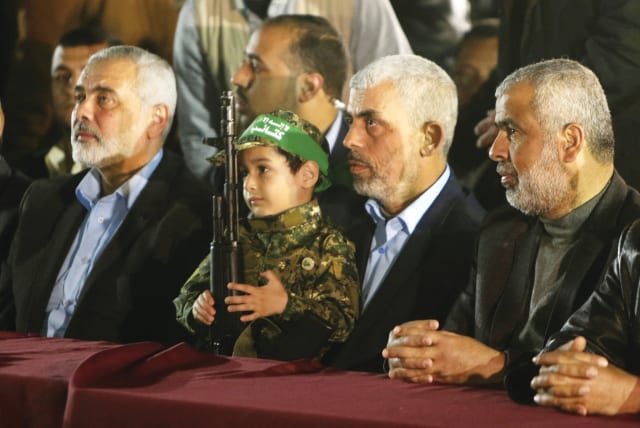  SENTENCED TO a life of hate and violence: A child in full Hamas regalia, flanked by movement heads Yahya Sinwar (2nd R) and Ismail Haniyeh, in Gaza City, 2017. (photo credit: MAHMUD HAMS/AFP via Getty Images)