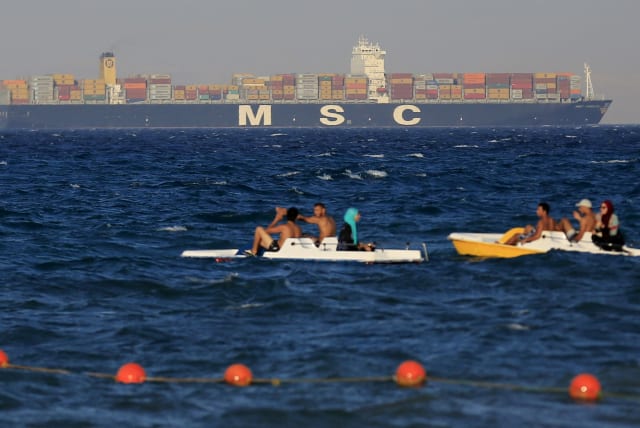  People enjoy the water as a container ship crosses the Gulf of Suez towards the Red Sea before entering the Suez Canal, in El Ain El Sokhna in Suez, east of Cairo, Egypt, September 5, 2015 (photo credit: Amr Abdallah Dalsh/Reuters)