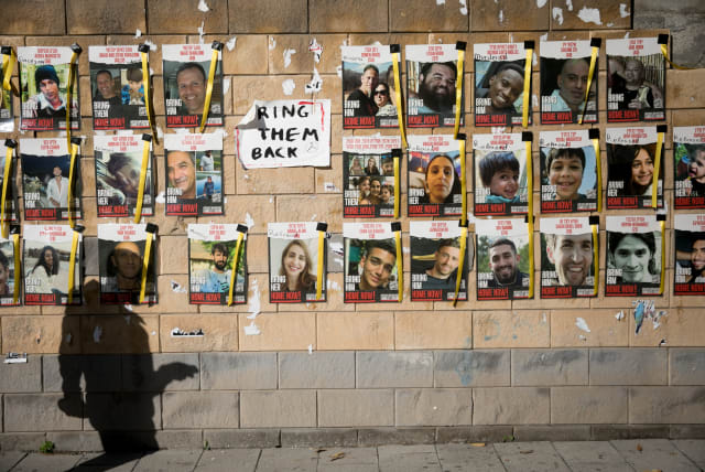  People walk by photographs of civilians held hostage by Hamas terrorists in Gaza, at "Hostage Square" in Tel Aviv. December 26, 2023.  (photo credit: MIRIAM ALSTER/FLASH90)
