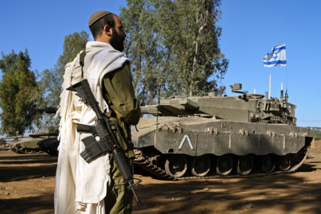  An Israeli soldier with a prayer shawl seen during a morning prayer near his tank near the border with Lebanon, northern Israel, October 25, 2023 (photo credit: MICHAL GILADI/FLASH90)