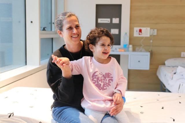  Abigail Idan, who was released after being taken hostage during the October 7 attack on Israel by the terrorist group Hamas, smiles on the lap of her aunt Liron at Schneider Children's Medical Center, November 27, 2023.  (photo credit: Schneider Children's Medical Center of Israel/Handout via REUTERS)