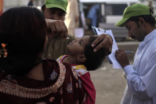  A polio worker administers polio vaccine to a child, who arrived from the Khyber-Pakhtunkhwa province, during a vaccination campaign at a bus stop in Rawalpindi May 13, 2014. (photo credit: REUTERS/Sara Farid)