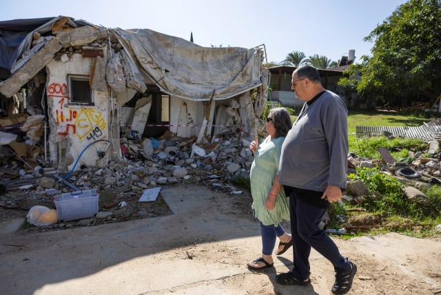  Ayelet Khon and Shar Shnurman walk past the remains of a home that was destroyed following the October 7 attack on Israel by Hamas, January 13, 2024 (photo credit: REUTERS/AMIR COHEN)