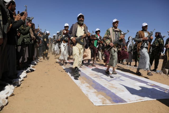 Tribesmen loyal to the Houthis march on U.S. and Israeli flags during a military parade for new tribal recruits amid escalating tensions with the U.S.-led coalition in the Red Sea, in Bani Hushaish, Yemen January 22, 2024. (photo credit: KHALED ABDULLAH/REUTERS)