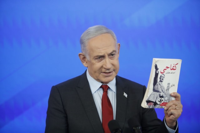 Prime Minister Benjamin Netanyahu holds an Arabic version of Adolf Hitler's Mein Kampf on January 27, 2024 (photo credit: TOMER APPELBAUM HAARETZ/POOL)