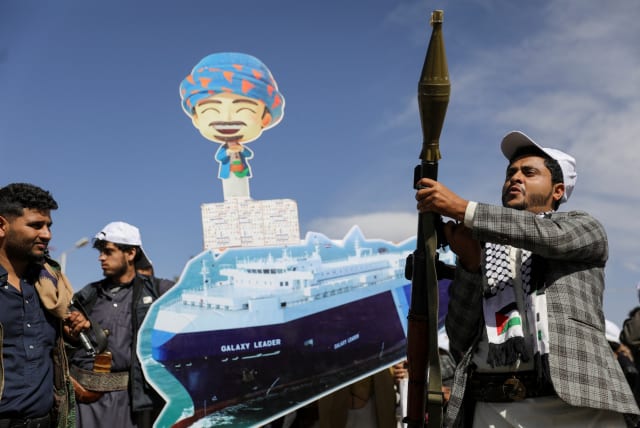  A Houthi follower holds a rocket launcher as others carry a cutout banner, portraying the Galaxy Leader cargo ship which was seized by Houthis, during a parade as part of a 'popular army' mobilization campaign by the movement, in Sanaa, Yemen, February 7, 2024. (photo credit: REUTERS/KHALED ABDULLAH)