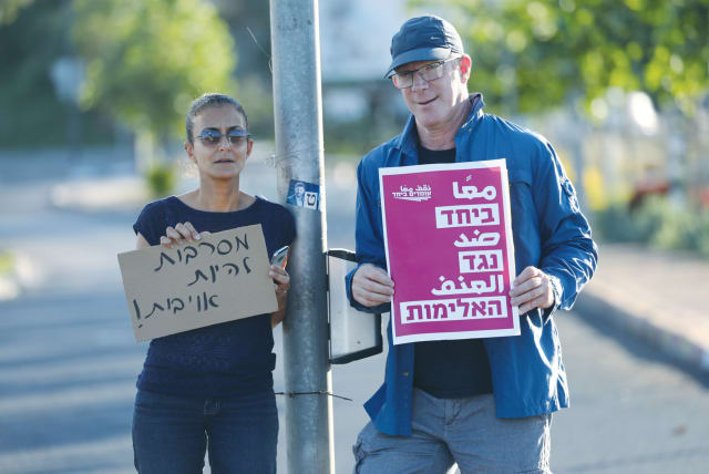  TWO DEMONSTRATORS hold signs at a protest calling for calm and Jewish-Arab coexistence in Lod in 2021, following a night of rioting by Arab residents in the city. The signs read: ‘We refuse to be enemies,’ and ‘Together against violence.’ (photo credit: YOSSI ALONI/FLASH90)