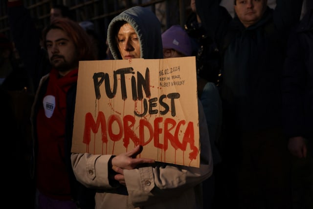 A woman holds a placard as people gather outside the Russian embassy, following the death of Russian opposition leader Alexei Navalny, reported by prison authorities in Russia's Yamalo-Nenets region where he had been serving his sentence, in Warsaw, Poland, February 16, 2024 (photo credit: Dawid Zuchowicz/Agencja Wyborcza/Reuters)
