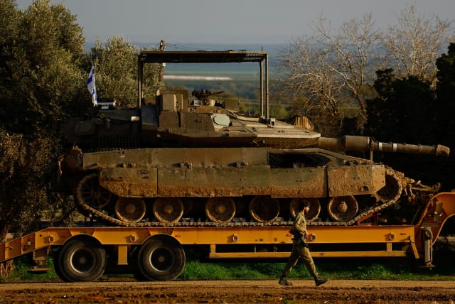  Israeli flags are seen as tanks and armoured personnel carriers wait to be unloaded outside Kibbutz Be'eri, February 18, 2024 (photo credit: REUTERS/SUSANA VERA)