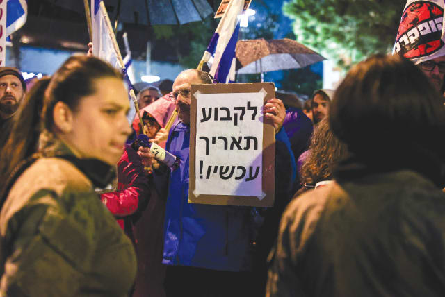  AT A PROTEST in Tel Aviv last month, a demonstrator holds a sign that reads: ‘Set a date now!’ a reference to the call for an early Knesset election. (photo credit: ITAI RON/FLASH90)