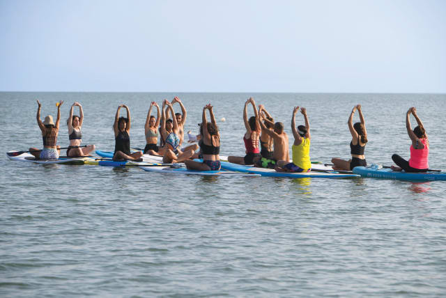 THERAPEUTIC ANCIENT art: Doing yoga on stand-up paddle boards during International Day of Yoga celebrations, in Lake Kinneret last June.  (photo credit: AYAL MARGOLIN/FLASH90)