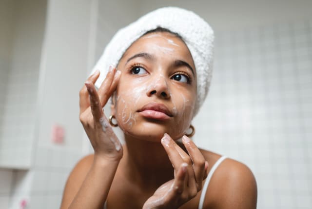  A woman is seen cleaning her face with facial cleanser. (photo credit: Ron Lach/Pexels)