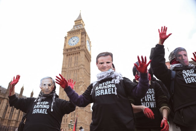  PRO-HAMAS protesters with red paint on their hands wear masks of UK Prime Minister Rishi Sunak, UK Foreign Secretary David Cameron, and Israeli Prime Minister Benjamin Netanyahu as they hold signs reading ‘Stop arming Israel,’ near Big Ben  in London, earlier this year. (photo credit: HOLLIE ADAMS/REUTERS)