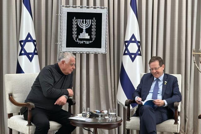  PRESIDENT ISAAC HERZOG smiles as he peruses Moshe Mizrahi’s memoir. (photo credit: OFFICE OF THE PRESIDENT)