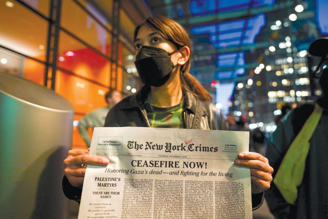  A protester holds a mock newspaper with a list of people killed in Gaza at a pro-Palestinian rally outside ‘The New York Times’ building in New York City on November 9, 2023.  (photo credit: David Dee Delgado/Reuters)