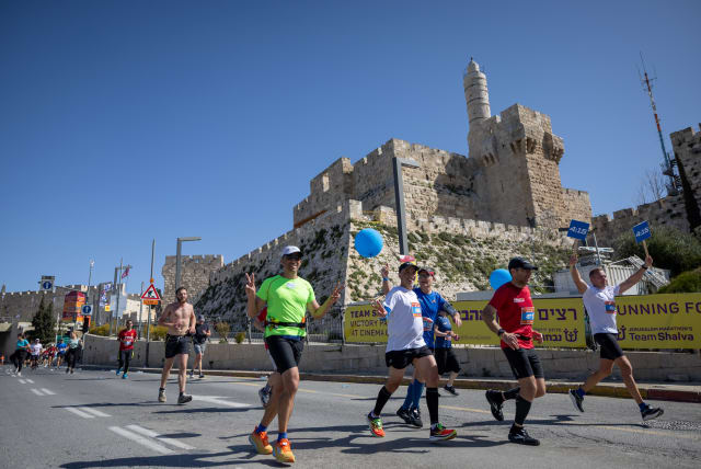  Thousands of runners pound the pavement in Jerusalem’s annual marathon, with part of the race near the Old City walls, March 17, 2023.  (photo credit: YONATAN SINDEL/FLASH90)