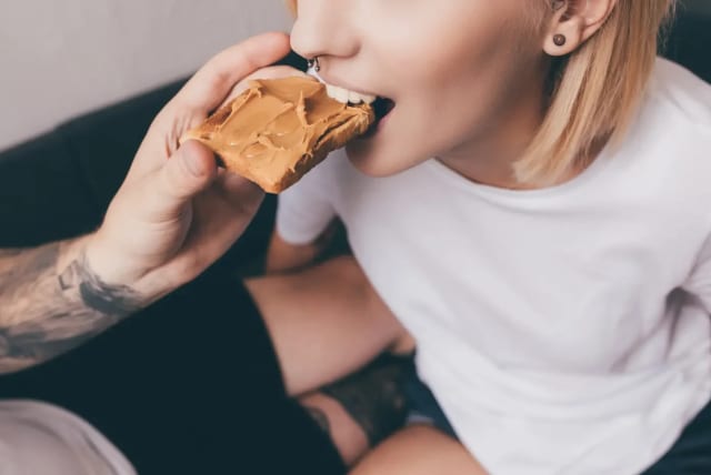   Young woman eating peanut butter (photo credit: SHUTTERSTOCK)