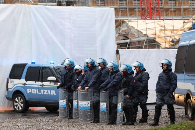  Police officers stand guard next to the Winter Olympics Village construction site, during a demonstration against Milan Cortina Winter Olympics 2026, in Milan, Italy, February 10, 2024.  (photo credit: Claudia Greco/Reuters)