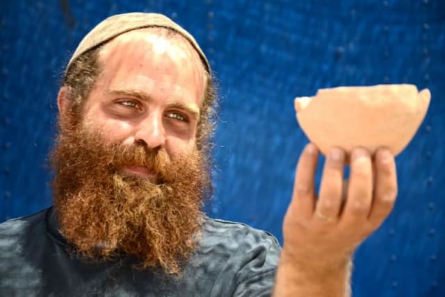  Benjamin Storchan holding findings from the escavation. (photo credit: SKYVIEW, COURTESY OF THE ISRAEL ANTIQUITIES AUTHORITY, YULI SCHWARTZ/IAA)