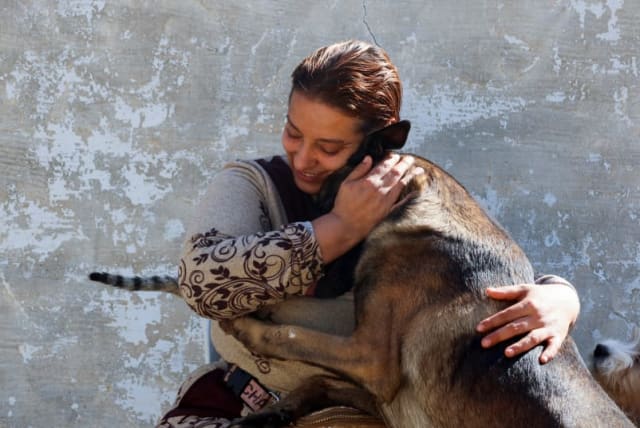  Una mujer tunecina, Houda Bouchahda, acaricia a un perro en una casa convertida en refugio donde, según ella, cuida ella sola de cientos de gatos heridos y docenas de perros, en Hammamet, Túnez 7 de marzo de 2024. (photo credit: REUTERS/JIHED ABIDELLAOUI)