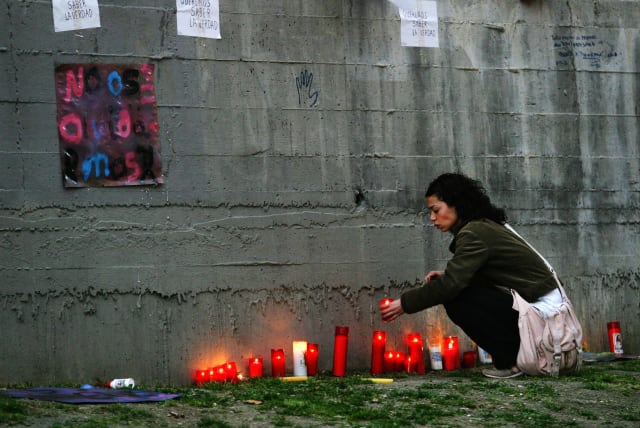  A woman lights a candle at a memorial site for the victims of the March 11 train bombings at the same spot where a train was bombed two years ago outside Madrid's Atocha station March 11, 2006. (photo credit: REUTERS)
