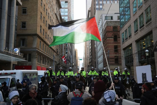  olice officers stand guard as supporters of a ceasefire in Gaza gather to protest near the venue of a Liberal Party fundraising rally featuring Canada's Prime Minister Justin Trudeau, amid the ongoing conflict between Israel and the Palestinian Islamist group Hamas, in Toronto, Ontario, Canada,  (photo credit: REUTERS/CARLOS OSORIO)