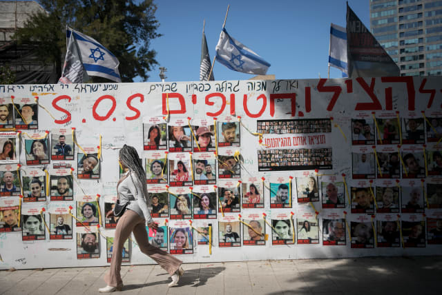  People walk by pphotographs of  Israelis still held hostage by Hamas terrorists in Gaza, at "Hostage Square" in Tel Aviv. March 10, 2024.  (photo credit: MIRIAM ALSTER/FLASH90)
