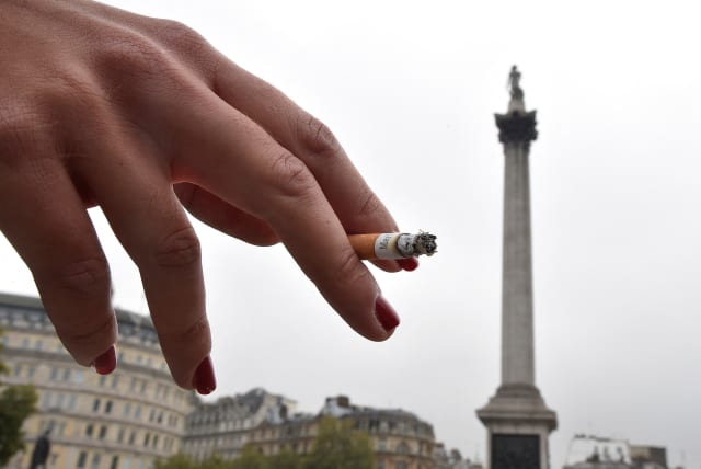  A woman holds her cigarette as she smokes in Trafalgar Square in central London October 15, 2014.  (photo credit: TOBY MELVILLE/REUTERS)