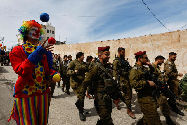  An Israeli settler takes part in celebrations marking the Jewish holiday of Purim, as IDF soldiers patrol, in Hebron in the West Bank March 7, 2023. (photo credit: MUSSA QAWASMA/REUTERS)