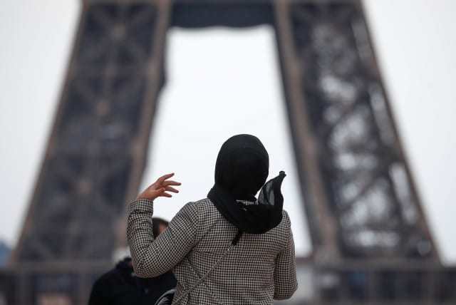  A woman wearing a hijab walks at Trocadero square near the Eiffel Tower in Paris, France, May 2, 2021. (photo credit: REUTERS/GONZALO FUENTES)